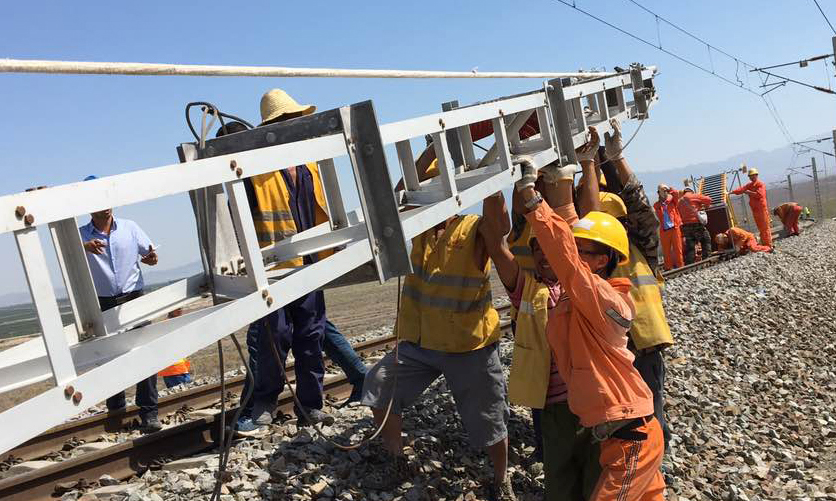 中国铁建抢修新疆精伊铁路，图为人工组立接触网钢柱。