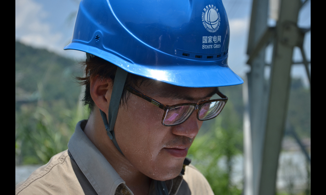 7月24日，福建福州供电公司输电运检室的工作人员头顶烈日对220千伏东高线进行巡视。 （陈蒸 摄）