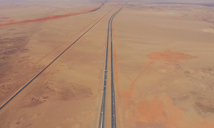 戈壁的大漠黄沙曾掩埋了无数西域古道，而如今一条大漠天路正顽强地与黄沙“搏斗”，在乌兰布和、腾格里、巴丹吉林三大沙漠中穿行，成为世界上最长的穿越沙漠高速公路，这就是北京至乌鲁木齐的京新高速公路。图为穿越戈壁的京新高速公路额济纳旗段（5月25日摄）。
