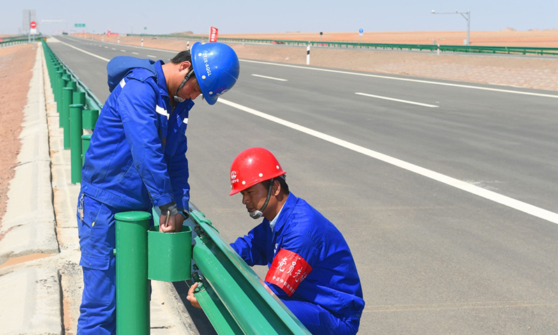 中国中铁京新高速公路总包部第七项目部的工作人员冒着高温在额济纳旗段检查护栏（5月25日摄）。