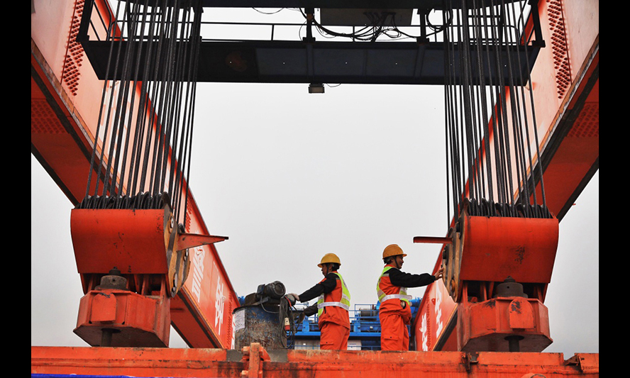 12月12日，在安六铁路岱港村特大桥，中铁五局工作人员操作设备架设箱梁。（新华社记者 刘续 摄）