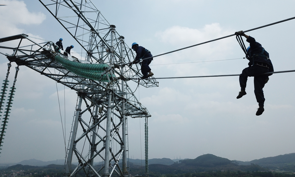 图为参加昆柳龙直流输电工程建设的南方电网广东电网能源发展有限公司高空作业人员在铁塔上展开金具安装。（陈海东 摄）