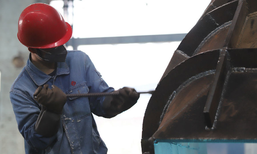 图为2月13日，广西建工集团冶建公司压力容器制造厂工人们戴口罩，经测体温后进入消毒过的生产车间进行生产作业。