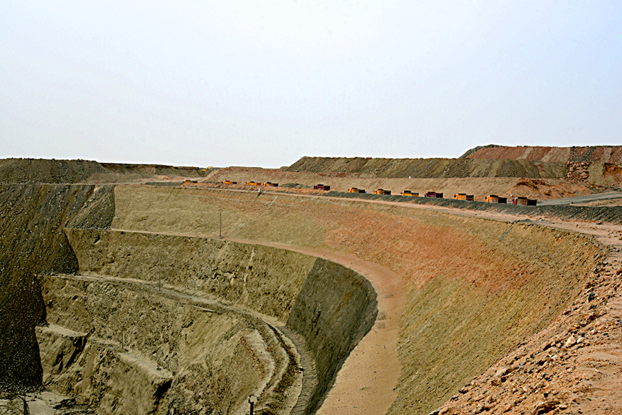 新疆磁海铁矿始建于上世纪90年代，地处新疆罗布泊野骆驼国家级自然保护区实验区边缘，地质环境主要为乱石沟壑遍布的戈壁滩。近年来，哈密市高度重视磁海铁矿生态环境恢复治理工作，全面关停了罗布泊野骆驼国家级自然保护区内的25家铁矿、有色金属、石材等矿山，关停了磁海铁矿一切生产经营活动，2018年底正式启动了磁海铁矿生态环境治理恢复再整改工程。图为中铁十九局新疆磁海铁矿生态环境治理恢复工程采坑上正在行进的施工车辆。（张振宇 摄）