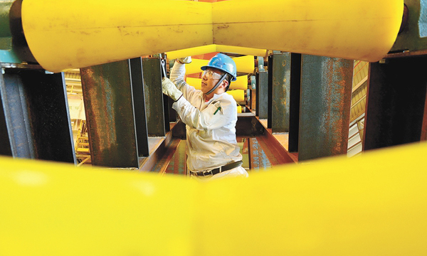 图为组块配套车间，一名施工人员正在为大型原油外输软管下水支架加装滚轮，为原油外输软管下水和安装做准备。