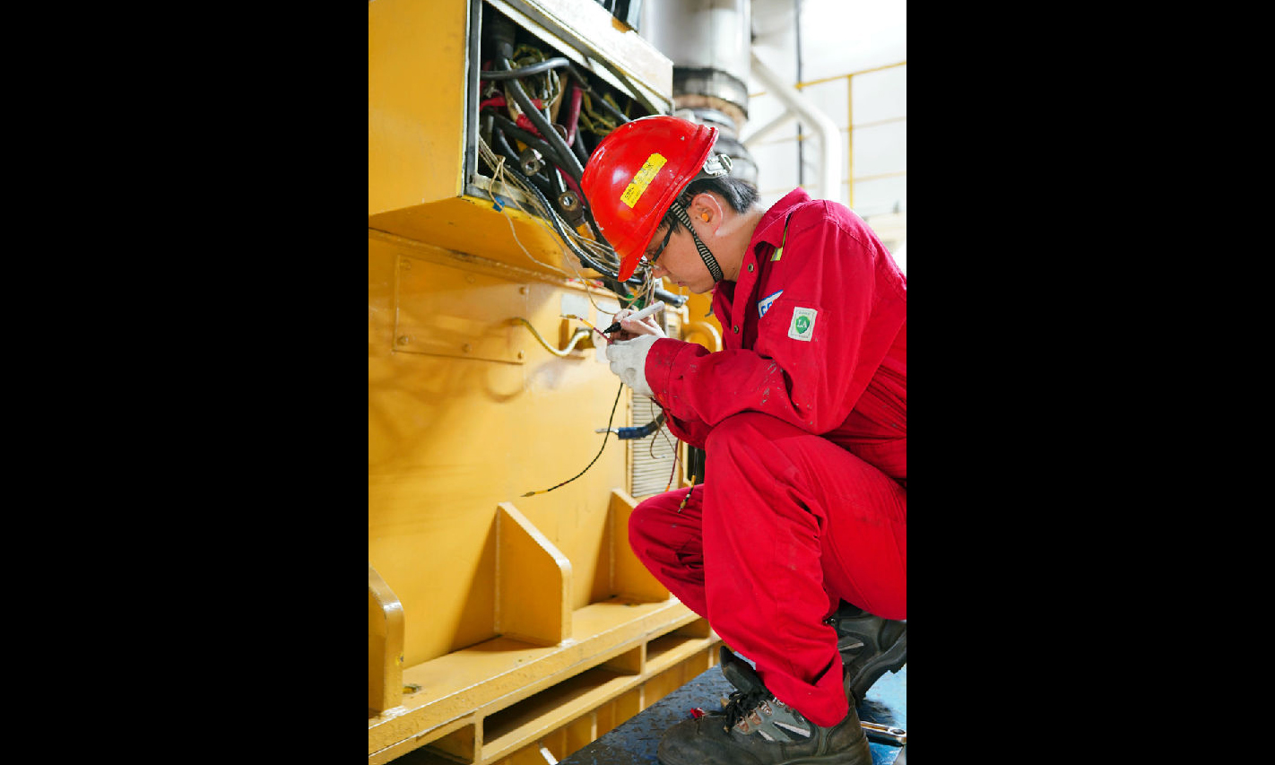 按照修理计划，“海洋石油923”钻井平台组织人员对1号柴油机进行修理。图为电气师正在检查柴油机电机接线。