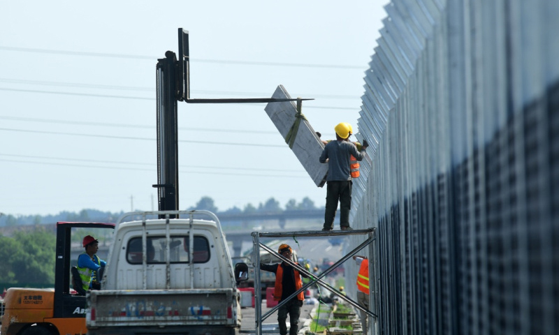 图为7月9日，工人在京哈高速长春至拉林河段改扩建工程现场为公路加装声屏障。（新华社记者 林宏 摄）