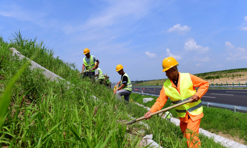 图为7月9日，工人在京哈高速长春至拉林河段进行绿化和引水道清理工作。（新华社记者 林宏 摄）