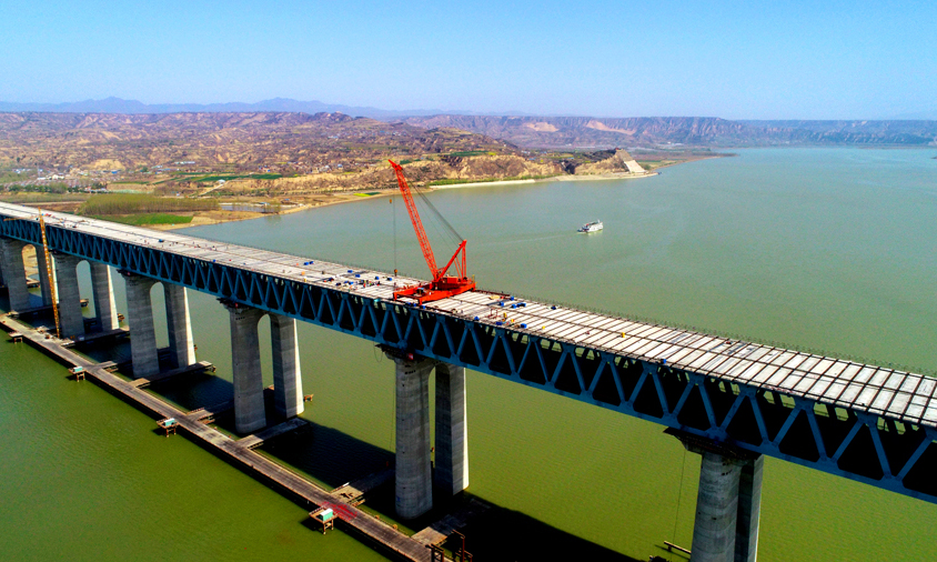 公路桥面板属于大桥公路层主体结构，共有大板760块，小板760块，单板最重32吨，总重量达2.5万吨。承载量大，设计结构复杂，桥面板外露钢筋与钢筋之间、钢筋与剪力钉之间设计间距小，桥面板结构尺寸大（长14.25米，宽3.42米），吊装高度达80米。图为三门峡黄河公铁两用大桥公路桥面板架设远景。