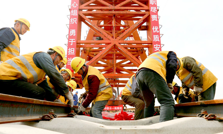 图为施工人员在蒙华铁路蛮河特大桥上进行铺轨作业。