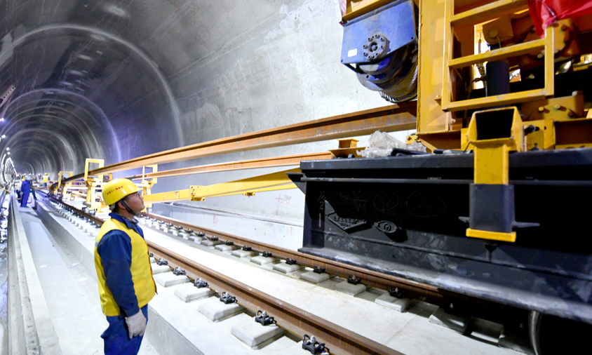 香嘎山隧道总长2478米，共需铺设8根500米长钢轨。为保证长钢轨运输和铺设安全、精准，施工前项目部专门制定了施工方案，现场进行严格的技术交底。图为工作人员在香嘎山隧道铺设长钢轨。