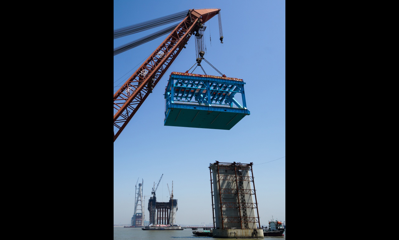 6月1日，施工人员在架设沪通长江大桥首个超千吨大节段钢梁。（新华社记者 李响 摄）