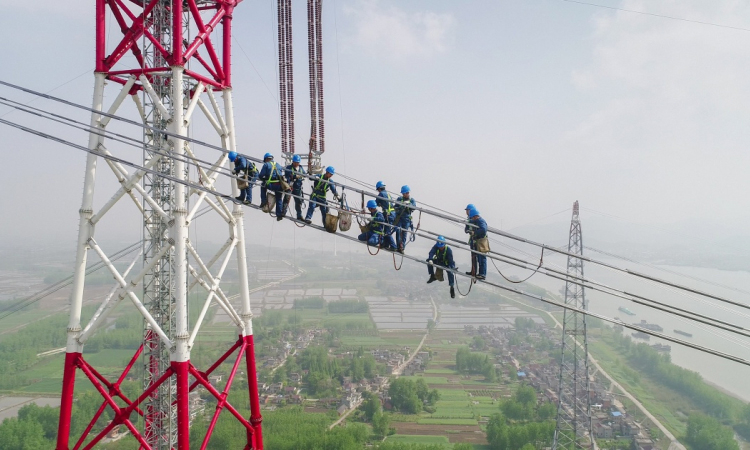 4月15日，在安徽省无为县高沟镇，工人们在昌古特高压长江大跨越工程跨越塔导线上进行高空作业（无人机拍摄）。