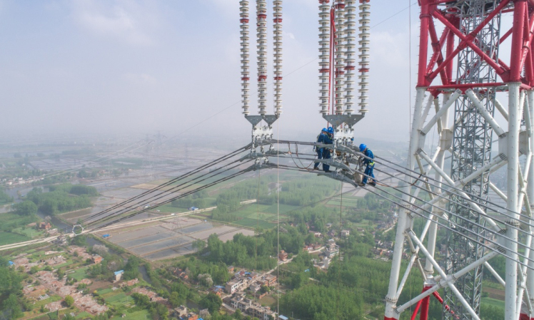 4月15日，在安徽省无为县高沟镇，工人们在昌古特高压长江大跨越工程跨越塔导线上进行高空作业（无人机拍摄）。