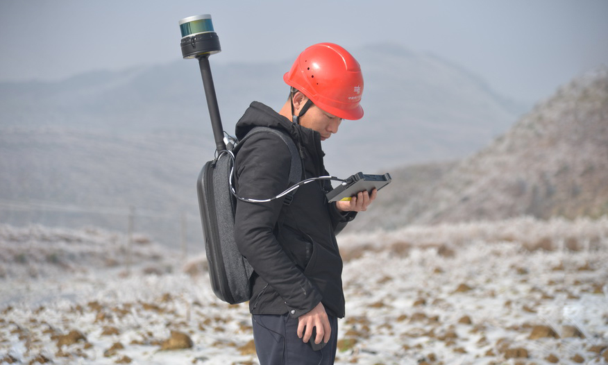 南方电网工作人员背着激光雷达进行线路扫描观测，仅用10分钟就完成了3档561米的覆冰导地线、铁塔和地形地貌采集。（于芳芳 摄）