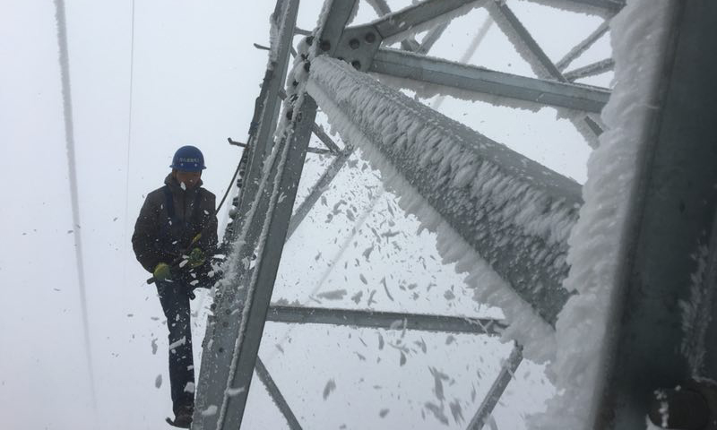 铁塔架构、附件上厚厚的覆冰仍需要人工消除。（赵新平 摄）