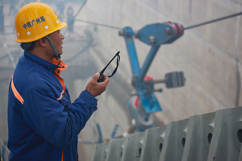 图为1月5日，一名工作人员在开州湖特大桥建设工地指挥主缆索股架设。（新华社记者 刘续 摄）