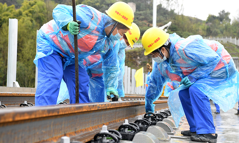 图为3月1日，在郑万高铁重庆段施工现场，施工人员进行铺轨作业。(新华社记者 唐奕 摄)
