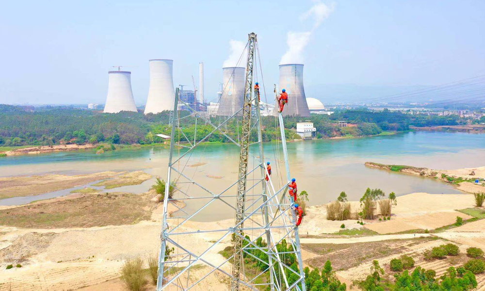 图为4月22日10时，广东河源，中国能建南方建投广东火电广东500千伏源和（河源）电厂二期接入系统工程，工作人员正在江边组塔。（林洁明 摄）