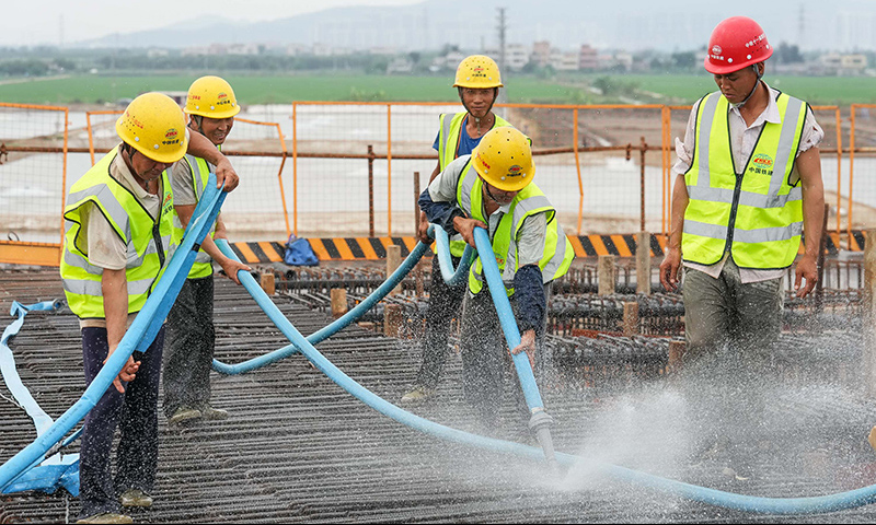 图为5月1日，工人在珠海鹤港高速公路二期工程高栏港枢纽立交桥建设现场冲洗箱梁底板。（新华社记者 刘大伟 摄）