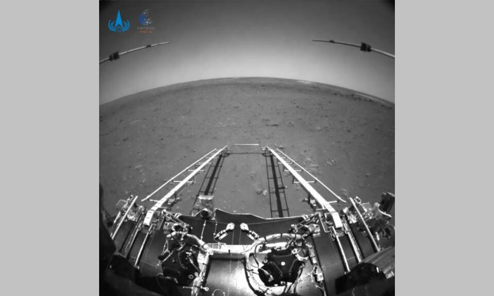 2021年5月19日，我国首次火星探测天问一号任务探测器着陆过程两器分离和着陆后火星车拍摄的影像发布。图像中，着陆平台和“祝融号”火星车的驶离坡道、太阳翼、天线等机构展开正常到位。该图由火星车前避障相机拍摄，正对火星车前进方向。图中可见坡道机构展开正常；图像上部的两个伸杆为已经展开到位的次表层雷达；前进方向地形清晰。为获知火星车前进方向更大范围的地形信息，避障相机采用大广角镜头，在广角镜头畸变的影响下，远处地平线形成一条弧线。