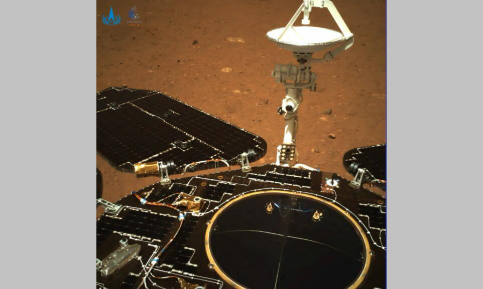 该图由导航相机拍摄，镜头指向火星车尾部。图中可见火星车太阳翼、天线展开正常到位；火星表面纹理清晰，地貌信息丰富。早在5月15日，天问一号任务着陆巡视器成功软着陆于火星乌托邦平原南部预选着陆区后，火星车建立了对地通信。5月17日，环绕器实施第四次近火制动，进入中继通信轨道，为火星车建立稳定的中继通信链路，陆续传回图像数据。目前，火星车正在开展驶离着陆平台的准备工作，将择机驶上火星表面，开始巡视探测。