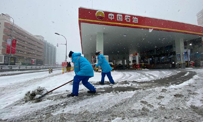  2月13日，中央气象台继续发布暴雪蓝色预警。大雪纷飞、气温骤降，让冬季保供的步伐越发急促。不管是在保障北京冬奥的加油站，还是在全力保障众多大中城市供气的长庆油田，不管是在绕29道弯山路的博孜1202井边，还是在环准噶尔盆地四千多公里油气战线上，中国石油员工不惧严寒坚守一线，用安全保供为万户千家送去温暖。图为距离鸟巢最近的石大第一加油站员工正在清雪。