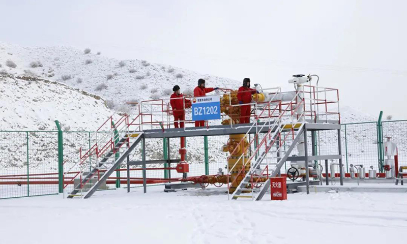 图为中国石油塔里木油田博孜1202井采气工对采气树积雪进行清理，防止雪水融化浸入电机引发故障。
