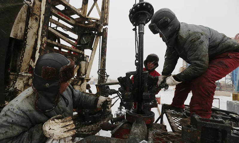 图为中国石油冀东油田一线工人冒雪抢座井口。