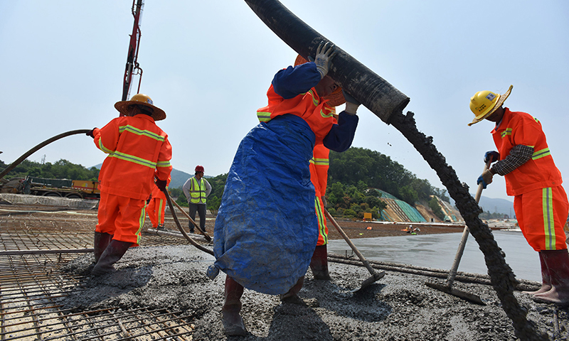该高速全线建成通车后，将实现深港两地“东进东出，西进西出”的大通关格局。图为施工人员在深圳东部过境高速简龙立交桥进行路面混凝土浇筑作业。