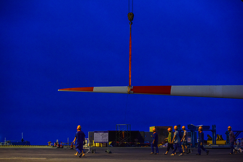 5月26日，施工人员从正在茂名广港码头进行总装的国内首台深远海浮式风电装备“扶摇号”一片风叶前经过。新华社记者 刘大伟 摄