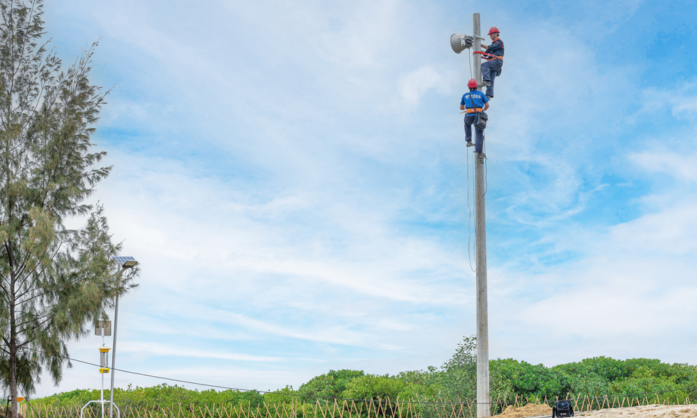 在广西，中国电信北海分公司装维人员爬上线杆安装天翼大喇叭。