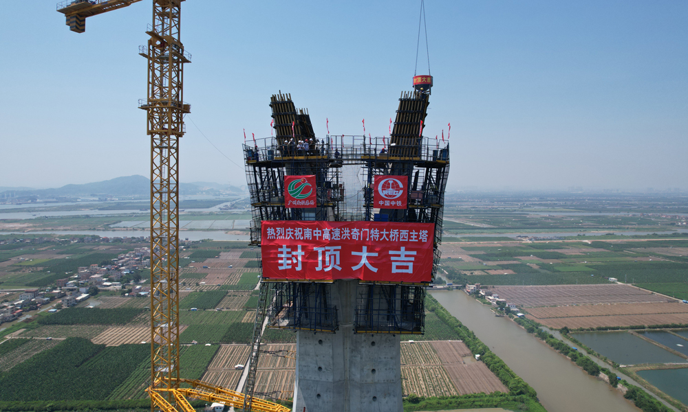 主塔采用全自动液压爬模系统进行施工，在主塔两肢合龙后逐渐向外倾斜展开，形成“花开”造型，这对液压爬模轨道在空中进行换轨带来了较大挑战。项目部将直轨道优化为与主塔线型契合的弧形轨道，在缩短每个节段施工周期的同时，也有效保障了塔柱高空施工作业安全。图为洪奇门特大桥西主塔封顶。