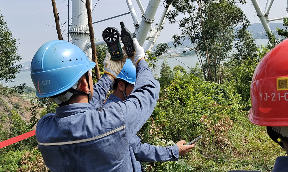在500千伏线路带电作业前，广东电网公司作业人员用测风仪和智能手机测试现场风力风速。