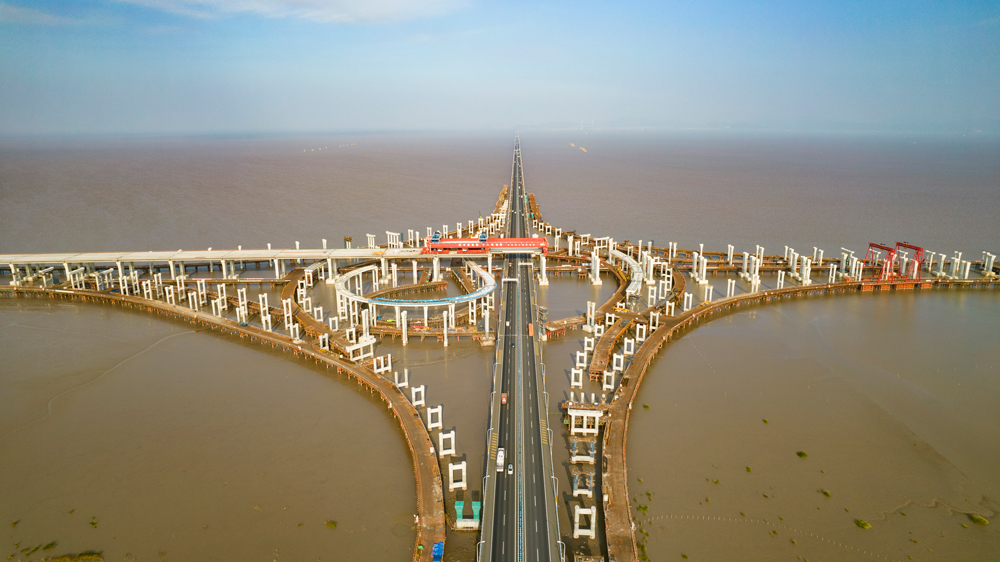 杭甬高速复线宁波一期工程全长55.833千米，为双向六车道高速公路标准，设计时速120千米。该工程主线桥在宁波市镇海区一跨直接越过甬舟高速金塘大桥，并设滨海互通与金塘大桥相接，主线桥箱梁梁底与金塘大桥桥面净空约7.6米，海上架梁施工安全风险极高，为全线唯一一处Ⅳ级施工风险点。图为滨海互通主线桥跨越金塘大桥架梁现场。