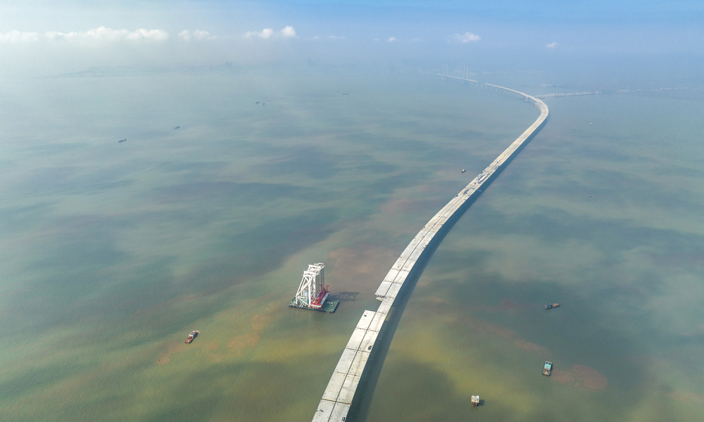 深中通道是集“桥、岛、隧、水下互通”于一体的跨海集群工程，全长约24公里。其中海上非通航孔桥共设293片混凝土梁和钢箱梁。梁体种类多，吨位重，架设精度要求高。本次架设混凝土梁单片长60米、宽20米、高3.5米，重约2800吨，相当于1800辆小轿车的重量，梁体顶部面积相当于3个标准篮球场。图为11月10日拍摄的深中通道施工现场。