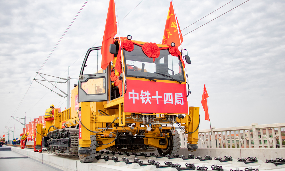 项目部克服异形梁、桥机频繁调头、高温暴雨、小曲线、大坡度等不利因素和架梁难题，先后使用下导梁罗盘调平技术、龙门吊安装走行纠偏装置、运梁车安装防疲劳人脸识别系统等先进技术和设备，将信息化运用到视频监控、风速监测、胎压监测、钢丝绳监测等各个方面，为箱梁架设做好技术和安全保障。图为多功能铺轨机。