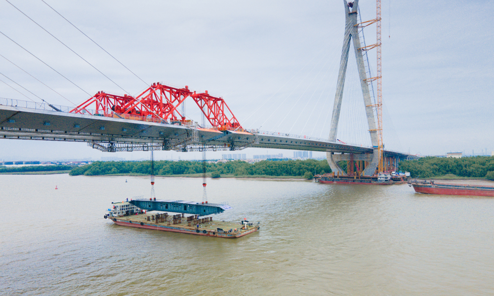 洪奇门特大桥是南中高速项目控制性工程之一，全长1126米，主跨520米，东西塔高分别178.5米、176米，为双塔双索面钢箱梁斜拉桥。大桥设计中融入了岭南人文景观元素，主塔形如木棉花开，造型轻巧活泼、挺拔秀美，寓有润泽湾区之意。图为5月21日拍摄的南中高速洪奇门特大桥合龙施工现场。