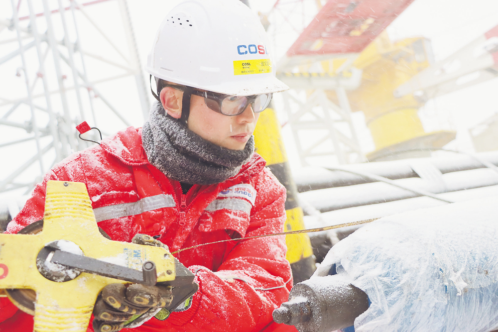“海洋石油923”钻井平台钻井队长在雪中测量钻井工具尺寸。 李国华 摄