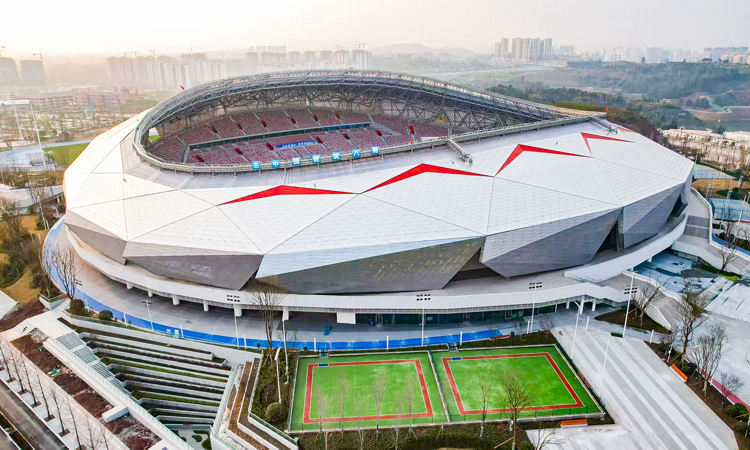 川渝广安共享体育基地总占地约308亩，建筑面积约8.2万平方米。整体规划采用“一场一馆”核心布局，包含体育场、体育馆两大主体建筑，并配套建设网球、羽毛球等室外运动场地，功能布局完善，可满足多元体育赛事与群众健身需求。