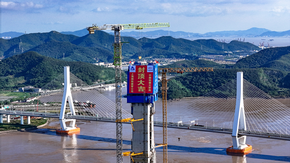 此次完成主塔封顶的富翅门公铁两用大桥跨越富翅门水道，连接舟山本岛与富翅岛，全长1725.85米，主跨388米，采用“公铁平层”布置，中间为双线铁路，两侧为双向六车道高速公路，是世界最大跨度高低塔公铁同层斜拉桥，也是世界首座桥塔中穿挑臂式钢箱梁斜拉桥。图为项目施工现场。