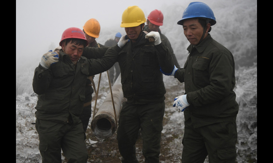 图为2月20日，在新化县郭家村，电力工人将电杆抬至倒杆处准备替换。（新华社记者 薛宇舸 摄）