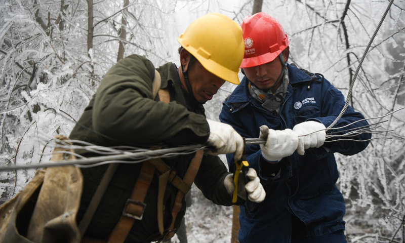 图为2月20日，在新化县郭家村，电力工人胡石东（左）和杨宏锋连接被覆冰压断的电线。（新华社记者 薛宇舸 摄）
