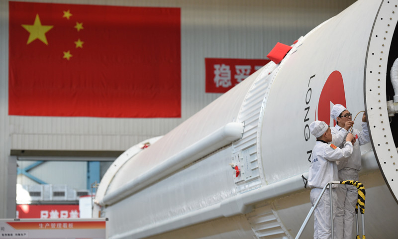 目前总体进展顺利，长征五号运载火箭整装待发。图为工作人员在天津新一代运载火箭产业化基地长征五号总装测试车间对火箭进行装配。