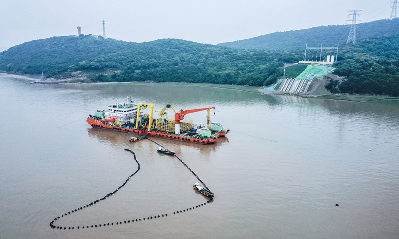图为6月2日，最后一段海底电缆从海缆施工船上缓缓拖向舟山大鹏山岛的终端站。（新华社记者 徐昱 摄）