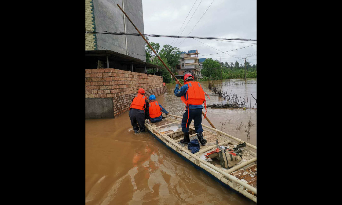 图为6月9日，江西永新县供电公司抢修员工划着木舟检查受损线路和供电设备。