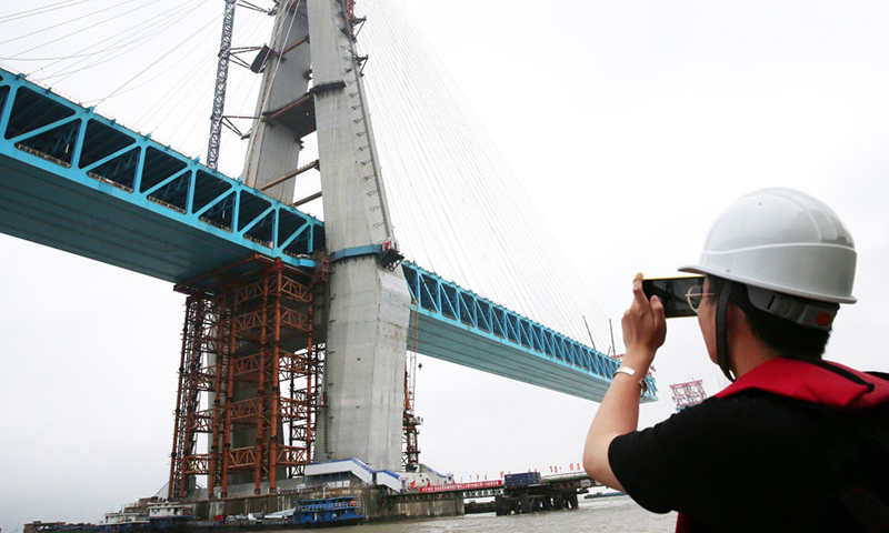 6月27日，沪通长江大桥南主塔顺利封顶。至此，该桥两座高达330米的主塔全部建成，标志着世界最大跨度公铁两用斜拉桥建设取得了关键性进展。图为6月27日，工作人员在拍摄沪通长江大桥南主塔。（新华社记者 许丛军 摄）