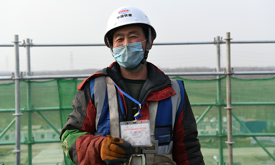 现场每名工人在上岗前都经过地方防疫机构检测和单位自查，合格后派发通行证，保证安全复工生产。图为工人展示通行证。（任双欢 摄）