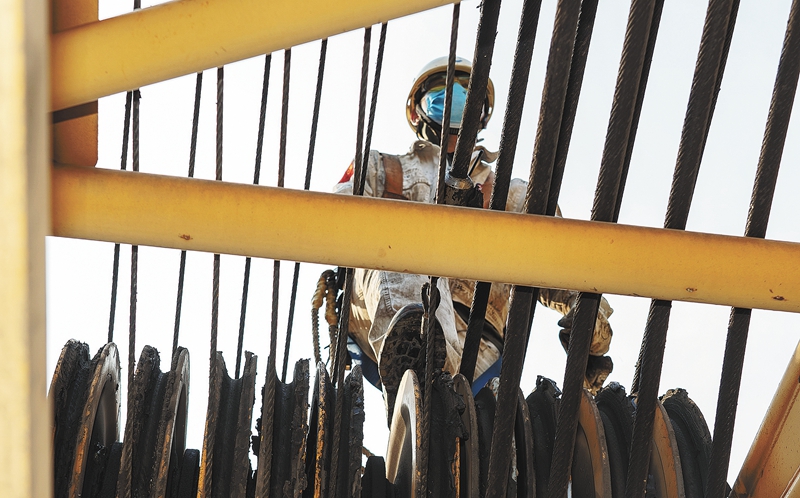 一名施工人员正在沿着臂杆走向检修点。