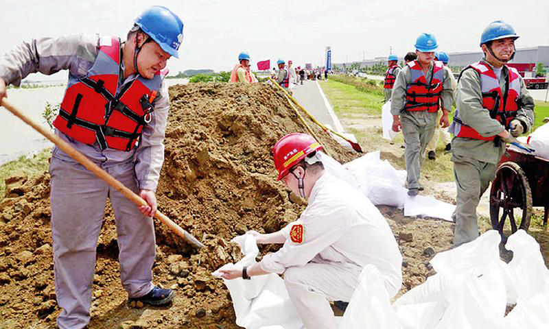 ７月以来，连续降雨天气导致长江中下游水位持续上涨，防洪抗汛形势异常严峻。越是关键时刻，越显国企担当。国家能源集团所属长江流域各单位闻“汛”而动，全面进入紧急战时状态，严守生命至上、安全第一防线，不畏艰难险阻，历经风雨洗礼，以实际行动除隐患保安全。为确保沿江子堤平安度汛，国华电力九江电厂派出一支由100余名员工组成的党员先锋队和青年突击队，对工业园沿江堤坝进行加高加固。图为7月12日，党员先锋队紧急填沙筑堤。